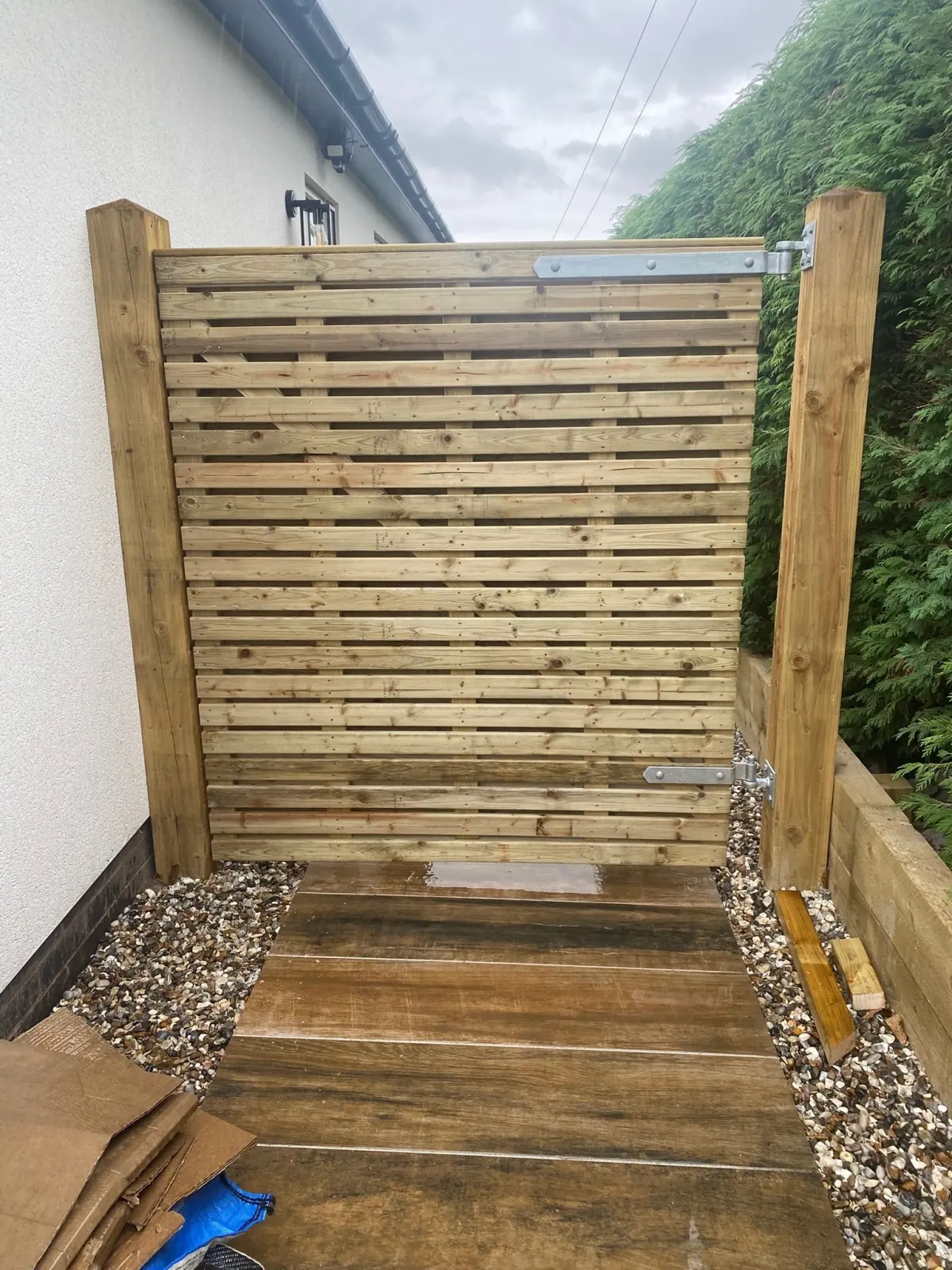 Contemporary slatted timber fence panel fitted between planed posts
